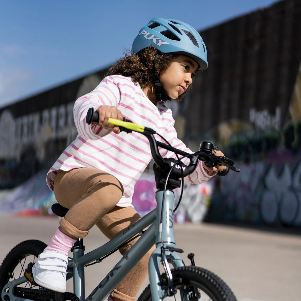 Barn som cyklar med en blå cykelhjälm från Puky på huvudet.