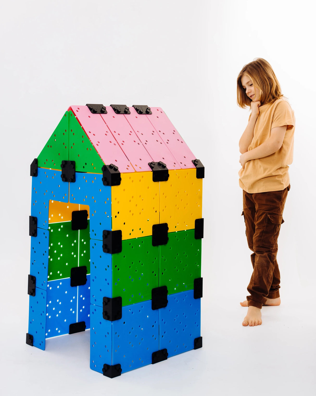 Barn tittar på ett ihopbyggt leksakshus från Eazymec i mixade färger