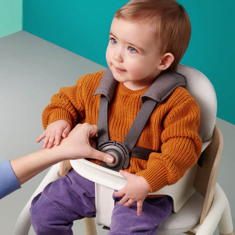 Litet barn sitter säkert i Bugaboo Giraffe-stolen med monterat babyset och justerbar fempunktssele.