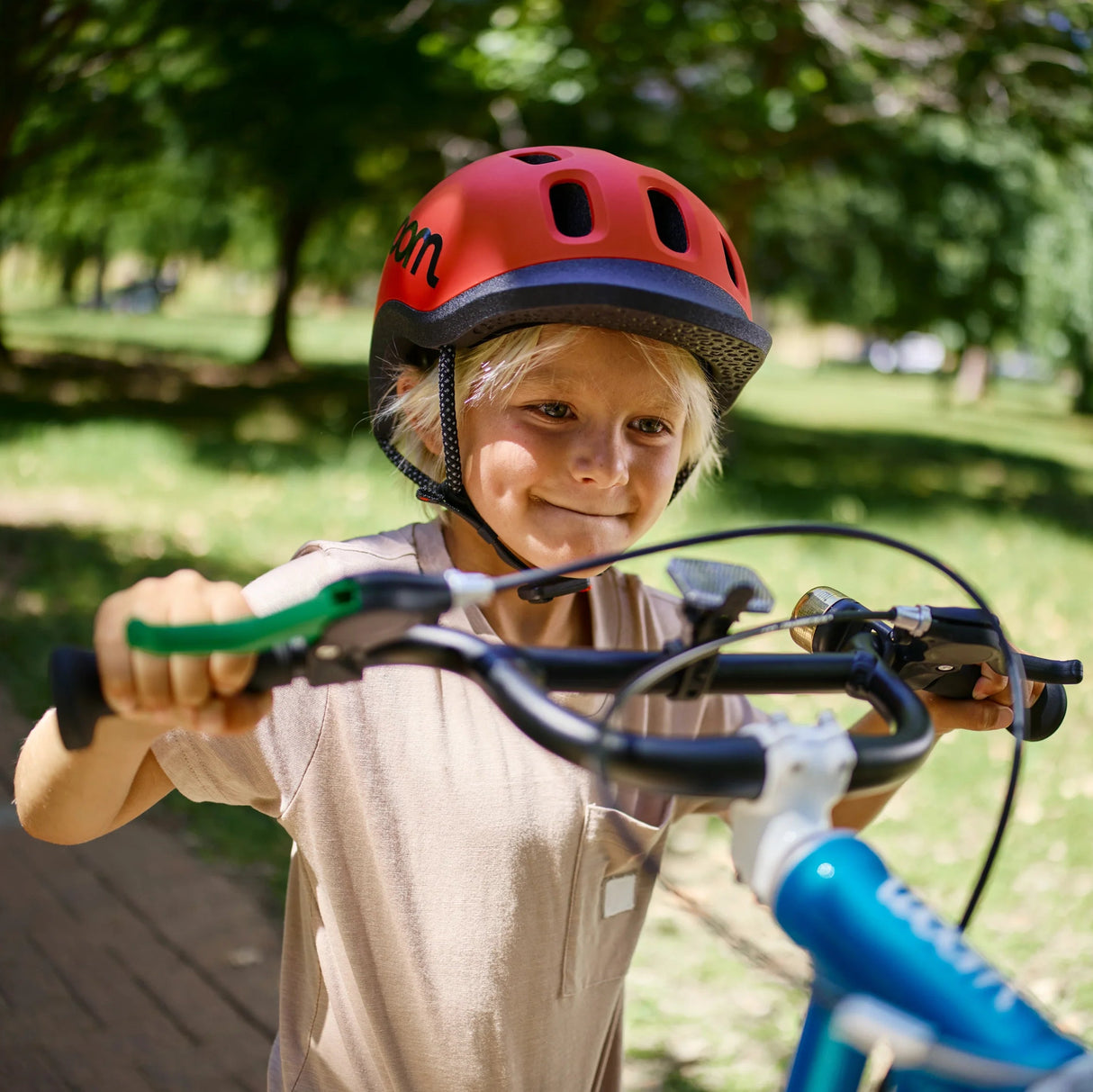Barn på Woom-cykel med Woom READY-barnhjälm i röd på sig